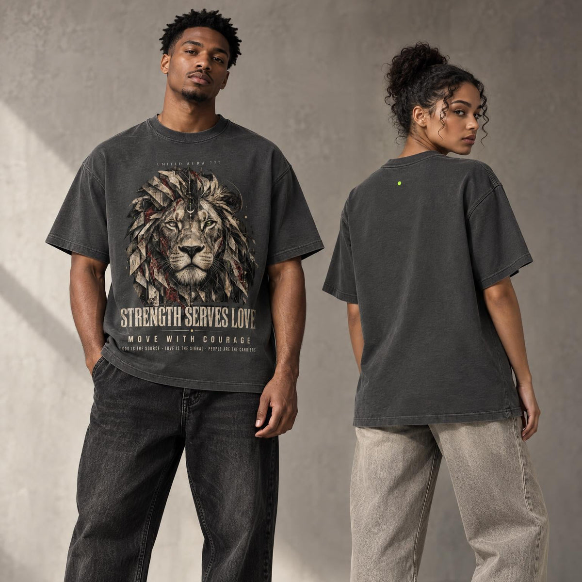 A man and a woman modeling oversized dark gray graphic t-shirts in a studio setting. The man is shown from the front wearing a dark gray t-shirt with a large lion graphic and the text 'STRENGTH SERVES LOVE' and 'MAKE WITH CROUCH'.