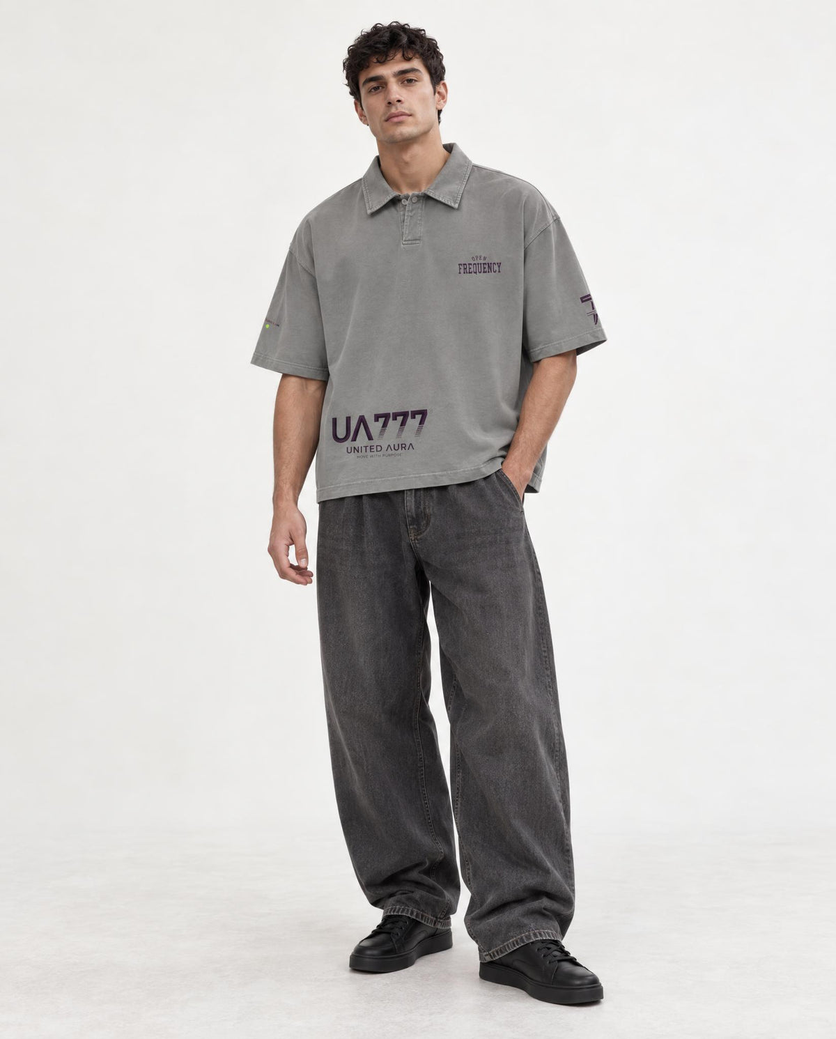 A man modeling a grey short-sleeve polo shirt with a cream-colored number 7 on the left chest, paired with matching navy drawstring pants and beige sneakers, against a plain light gray studio background.