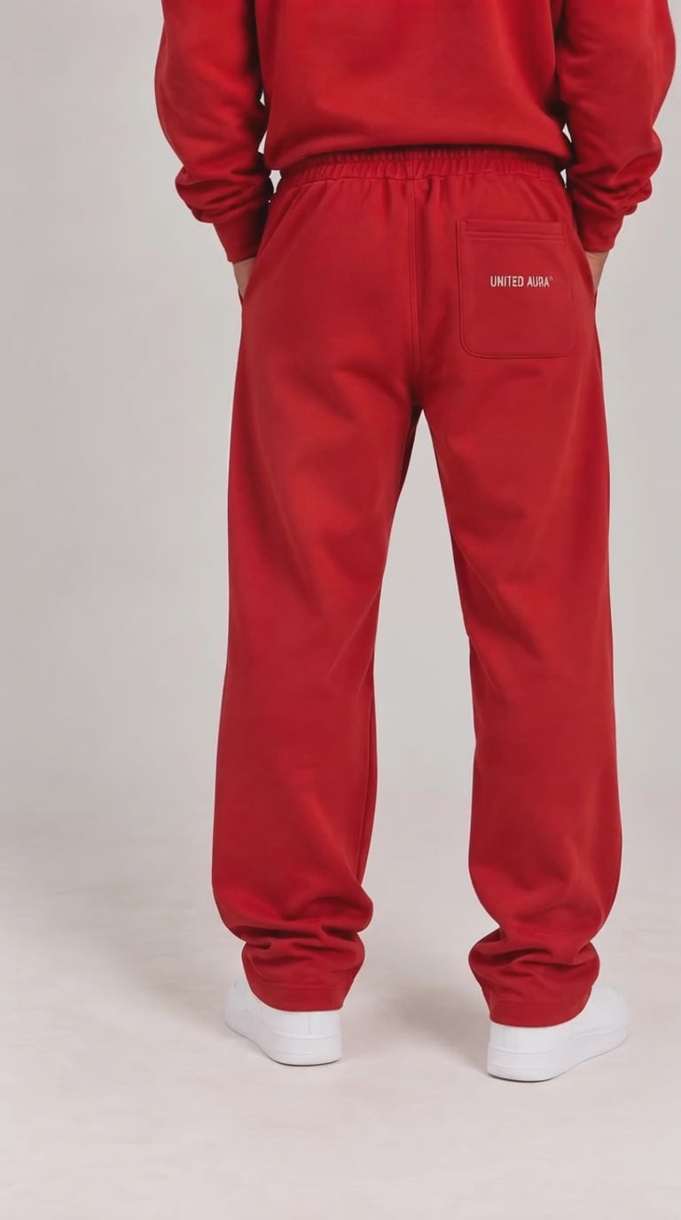 video of A person shown from the back wearing red sweatpants with a small white 'UNITED ARMY' logo on the back pocket, paired with a matching red sweatshirt and white sneakers, against a light gray studio background.