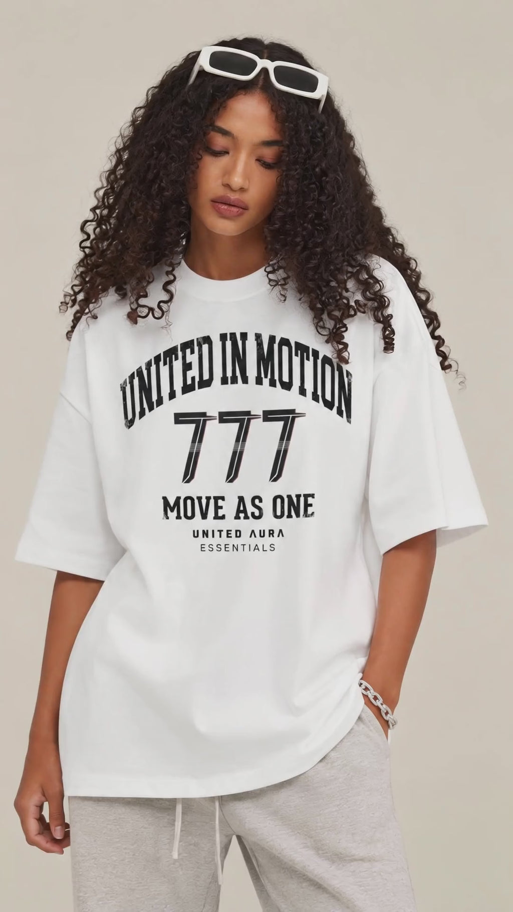 white oversized UNITED ΛURΛ 777 T-shirt shown on a model in a premium fashion campaign video, highlighting the relaxed fit, heavyweight fabric, and signature OPEN FREQUENCY design.